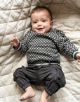 Adorable baby wearing the Nordic Cotton Knit Jumper in a grey and white pattern, made from soft cotton for comfort and warmth. Ideal for chilly days, this sweater adds a cozy and stylish touch to any outfit.