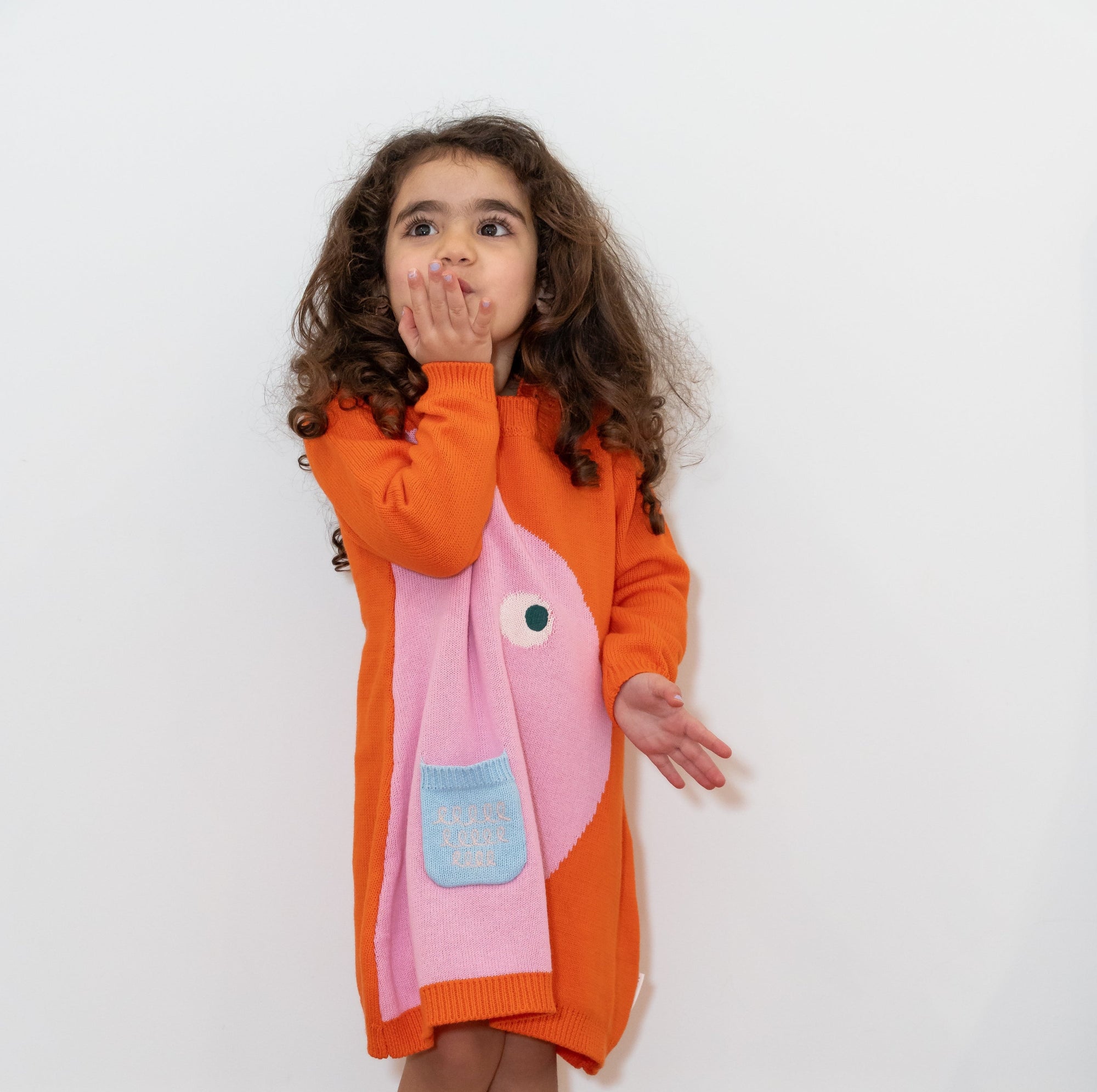 Adorable toddler in Chirpy Bird Cotton Knitted Sweater Dress, bright orange with a playful pink bird design and front pocket. Long-sleeved, cozy cotton perfect for fall/winter, ideal for casual wear.