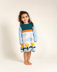 Toddler wearing Cloudy Daydream Cotton Knitted Sweater Dress featuring soft blue sleeves, cloud patterns, yellow tulips, and an orange stripe. Cozy, long-sleeved, ideal for fall/winter casual outfits.